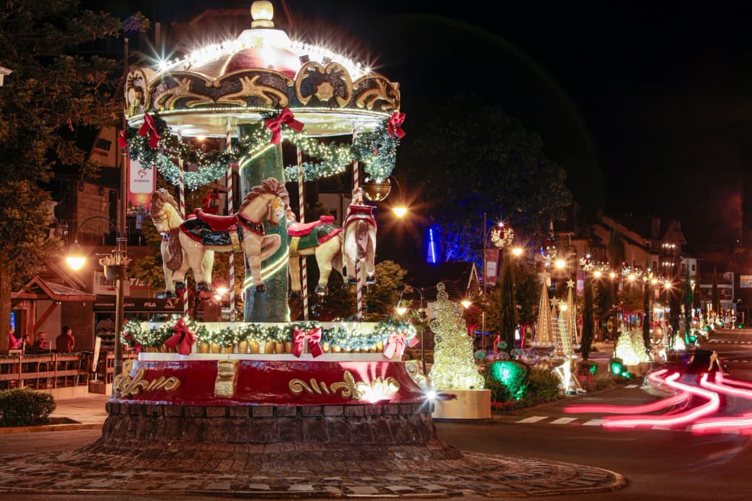 Rua de Gramado decorada e iluminada durante o Natal Luz, com árvores de luz e público caminhando.